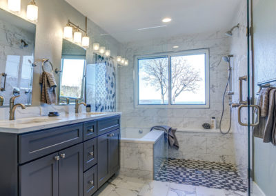 Gorgeous renovated bathroom with new tiles, double vanity, and glass shower enclosure