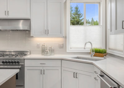Bright and modern renovated kitchen with white shaker panel cabinets and sleek finishes. The kitchen features a large center island with seating, perfect for entertaining