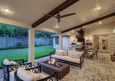 Beautifully renovated outdoor area with new landscaping and a modern patio. The space is perfect for entertaining with a built-in grill and seating area. The outdoor fireplace creates a cozy atmosphere for cooler evenings. The green grass and colorful flowers add a touch of nature to the space