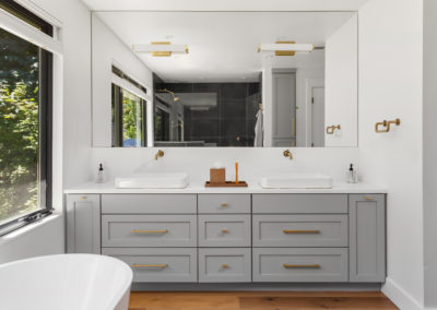 custom made grey double vanity with gold fixture and free standing tub. sophisticated and luxury look