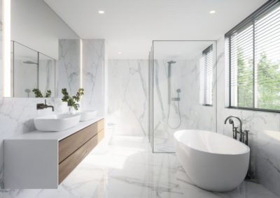 Luxury renovated white bathroom with marble tiles, free standing tub, and custom made white and paige vanity - sophisticated and elegant design