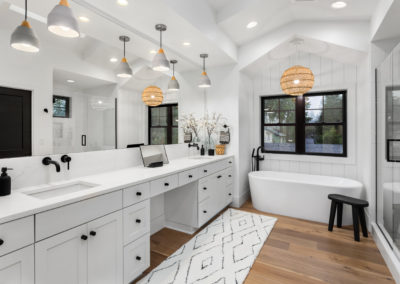 Bathroom in luxury home with double vanity, free standing bathtub, mirror, sinks, shower, and hardwood floor