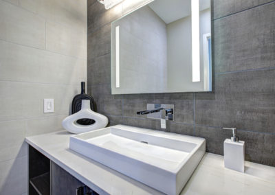 Contemporary bathroom interior with tile wall surround in grey tones.