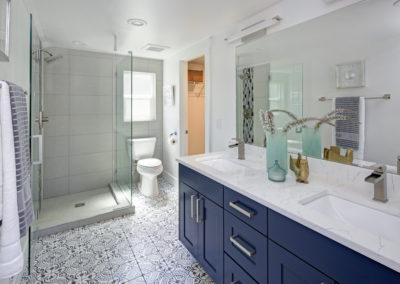 Modern bathroom interior with blue double vanity and glass shower.