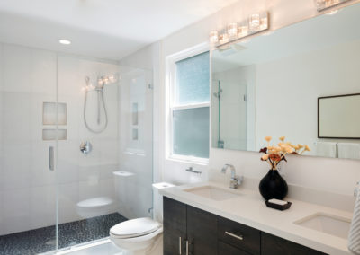 Renovated bathroom with custom made double vanity and white tiles for shower, built in niche