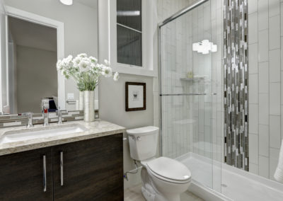 Renovated shower with classic subway tile and a warm brown vanity