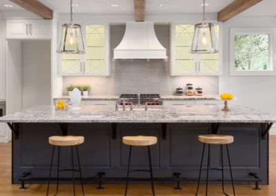 Elegant renovated kitchen with white shaker panel cabinets featuring frosted glass doors and a grey center island. The open concept design and natural light create a spacious and inviting atmosphere. The white and grey color scheme adds a modern and inviting touch to the space, perfect for entertaining or relaxing with family. Features include new appliances and sleek quartz countertops