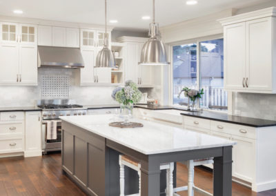 Gorgeous renovated kitchen with white shaker panel cabinets and a large grey center island. The open concept design and natural light create a spacious and inviting atmosphere. The white and grey color scheme adds a modern and inviting touch to the space, perfect for entertaining or relaxing with family. Features include new appliances and sleek quartz countertops