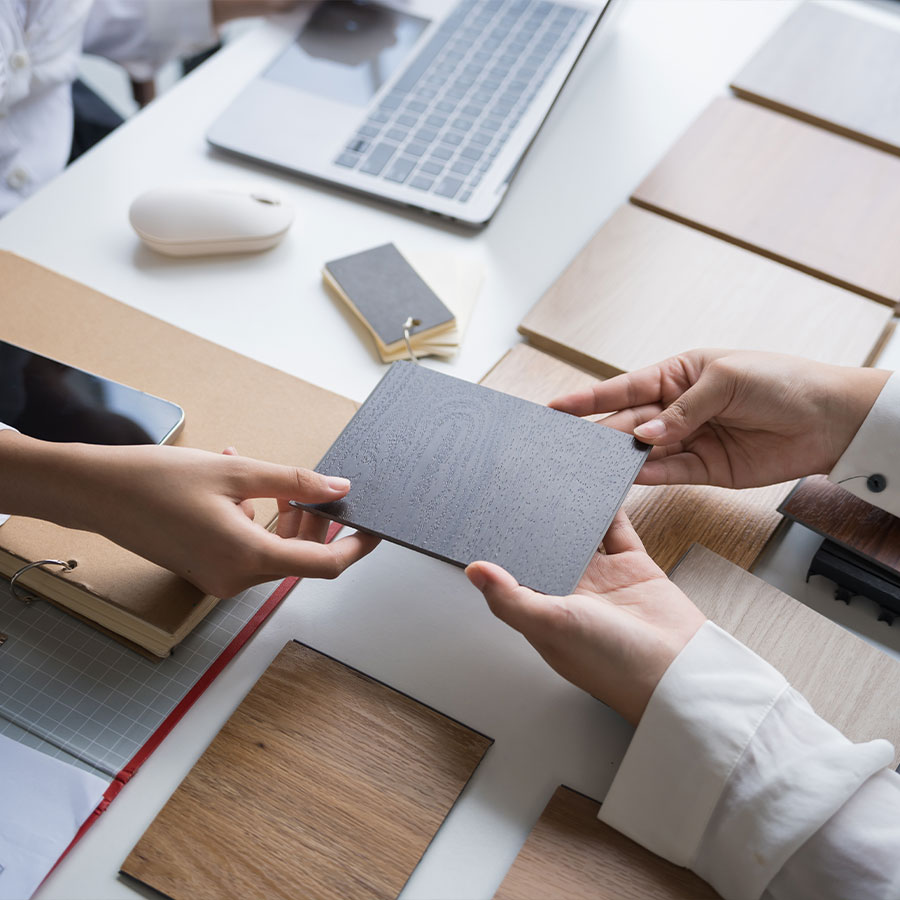 In-house interior design consultation by Magnum Construction Services showing designers reviewing wood and laminate samples for high-end home renovation projects in Vancouver.